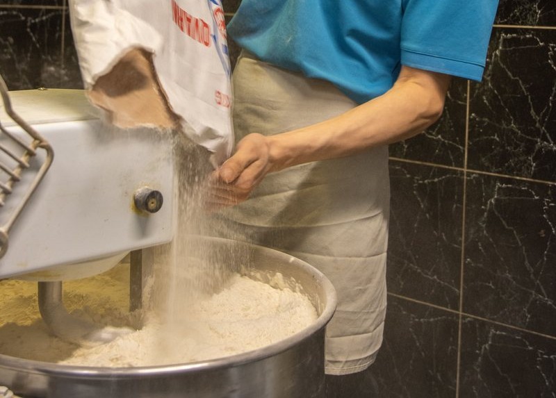 Wheat flour being sifted into a stainless bowl