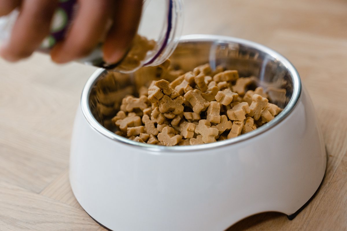 Extruded pet food kibble in a wooden bowl