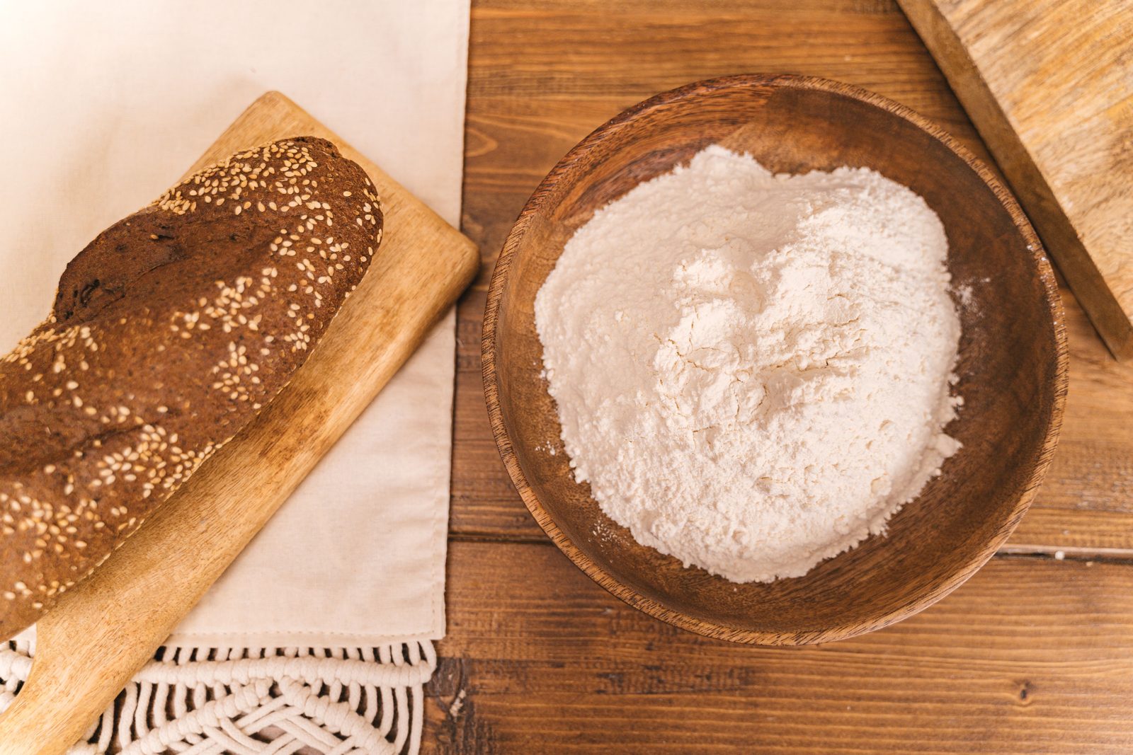 Vital wheat gluten powder beside a loaf of bread and a bowl of flour